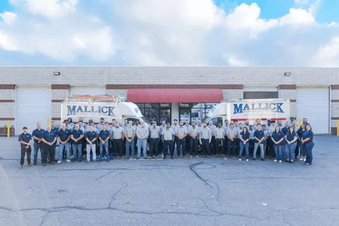 The full Mallick Plumbing & Heating team with service trucks