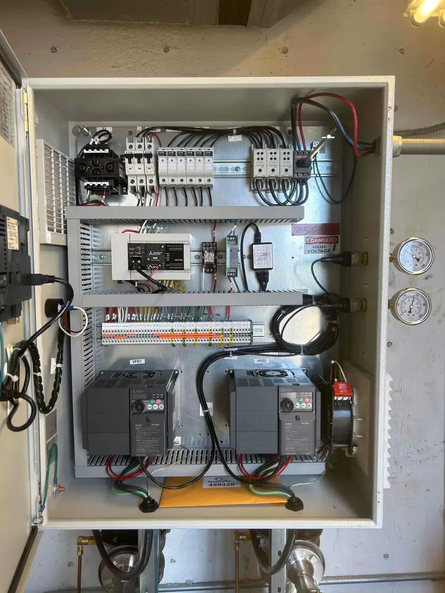 Interior of a newly installed commercial pump control panel with breakers and variable-frequency drives