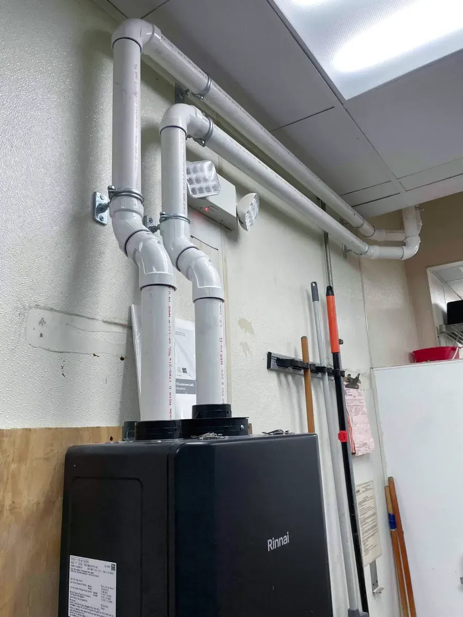 Rinnai commercial tankless water heater with PVC venting mounted on a wall in a Gaithersburg restaurant